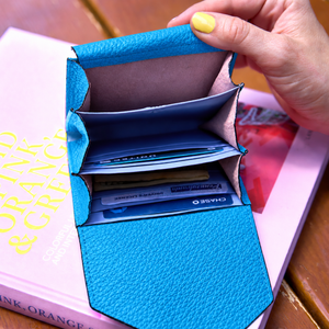 Tusk 382 Ascot Origami Wallet in Azure Italian pebble-grain cowhide leather. Lifestyle view held open, showing matching pebble-grain leather flap and original lavender-blue dividers - AZURE