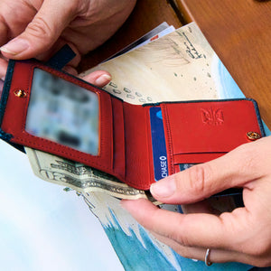 Red wallet leather interior with money and cards held by hands on a wooden surface - NAVY