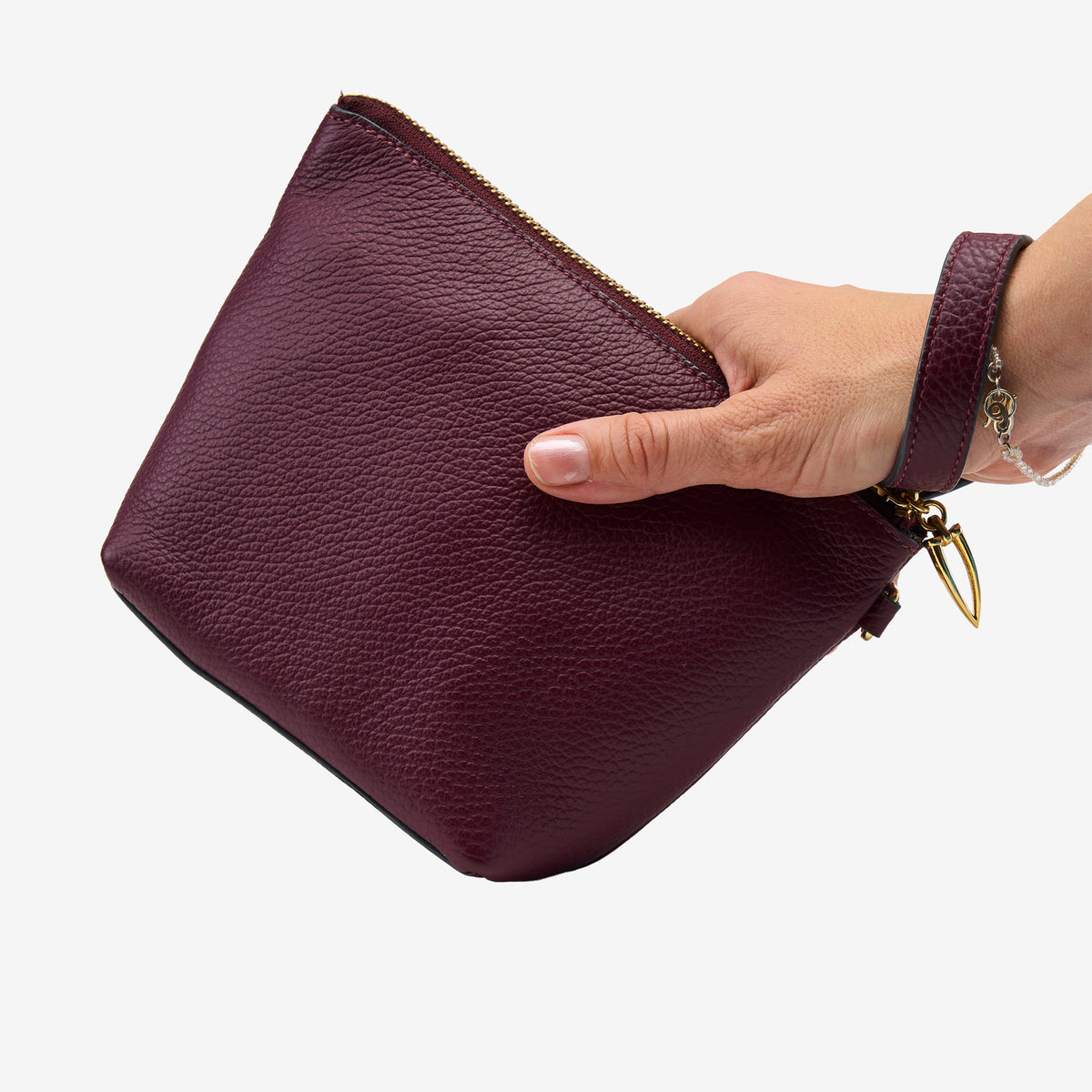Hand holding a maroon leather clutch bag on a white background - OXBLOOD