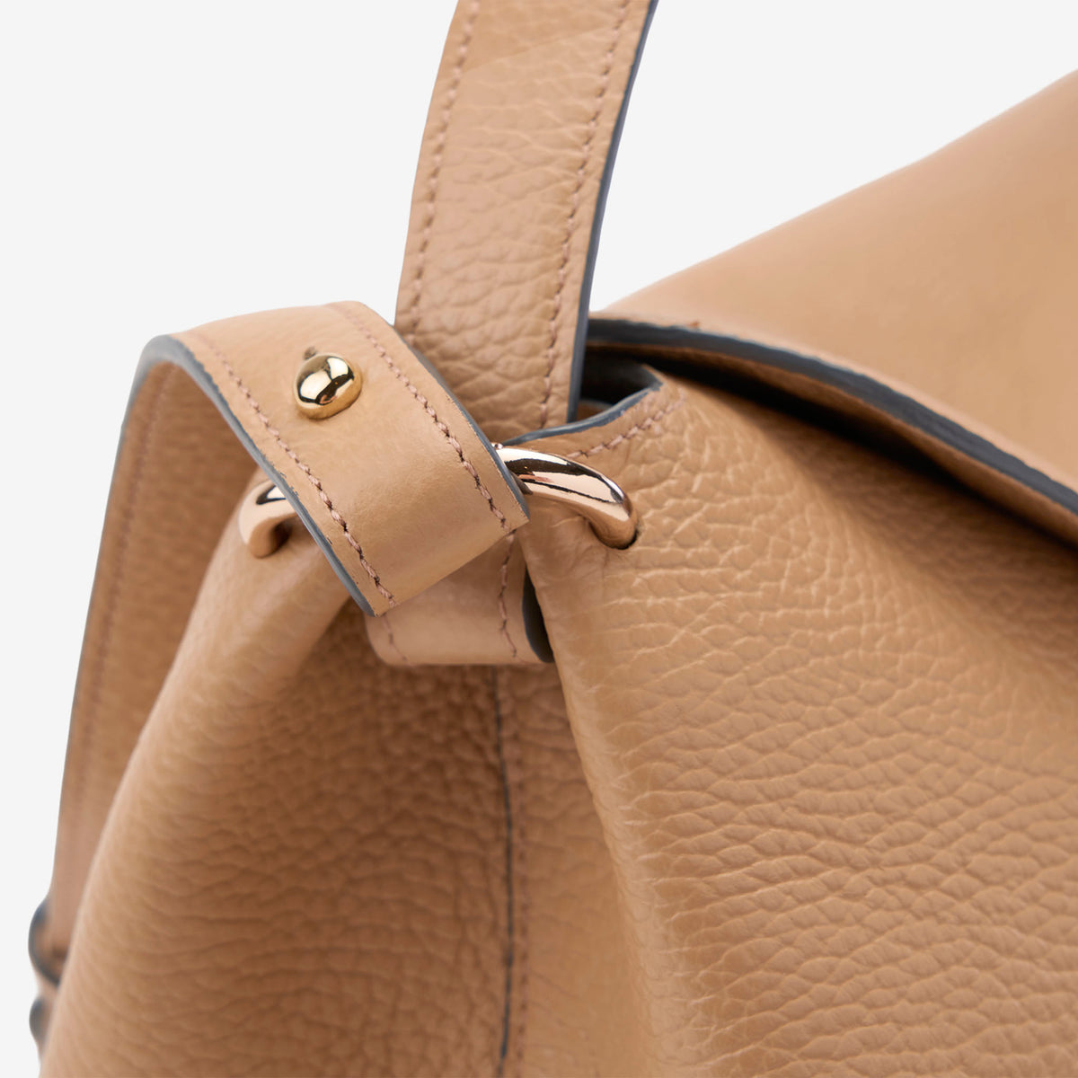 Close-up of a beige Italian leather handbag with gold accents on a light gray background - SAND