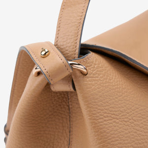 Close-up of a beige Italian leather handbag with gold accents on a light gray background - SAND