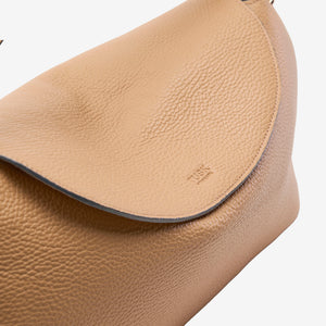 Close-up of a beige Italian leather bag with a visible brand logo on a white background - SAND