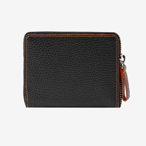 Back view of the Tusk Amsterdam men's zip-around wallet in black pebble leather, showcasing bright orange contrast perimeter stitching and a black leather zipper pull tab with orange trim on a white background - BLACK