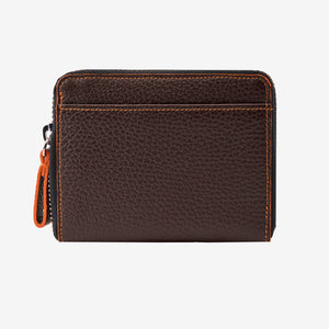 Tusk Amsterdam leather zip-around wallet in chocolate brown pebble leather, featuring a compact design with bright orange contrast stitching and an orange zipper pull tab on a white background - CHOCOLATE