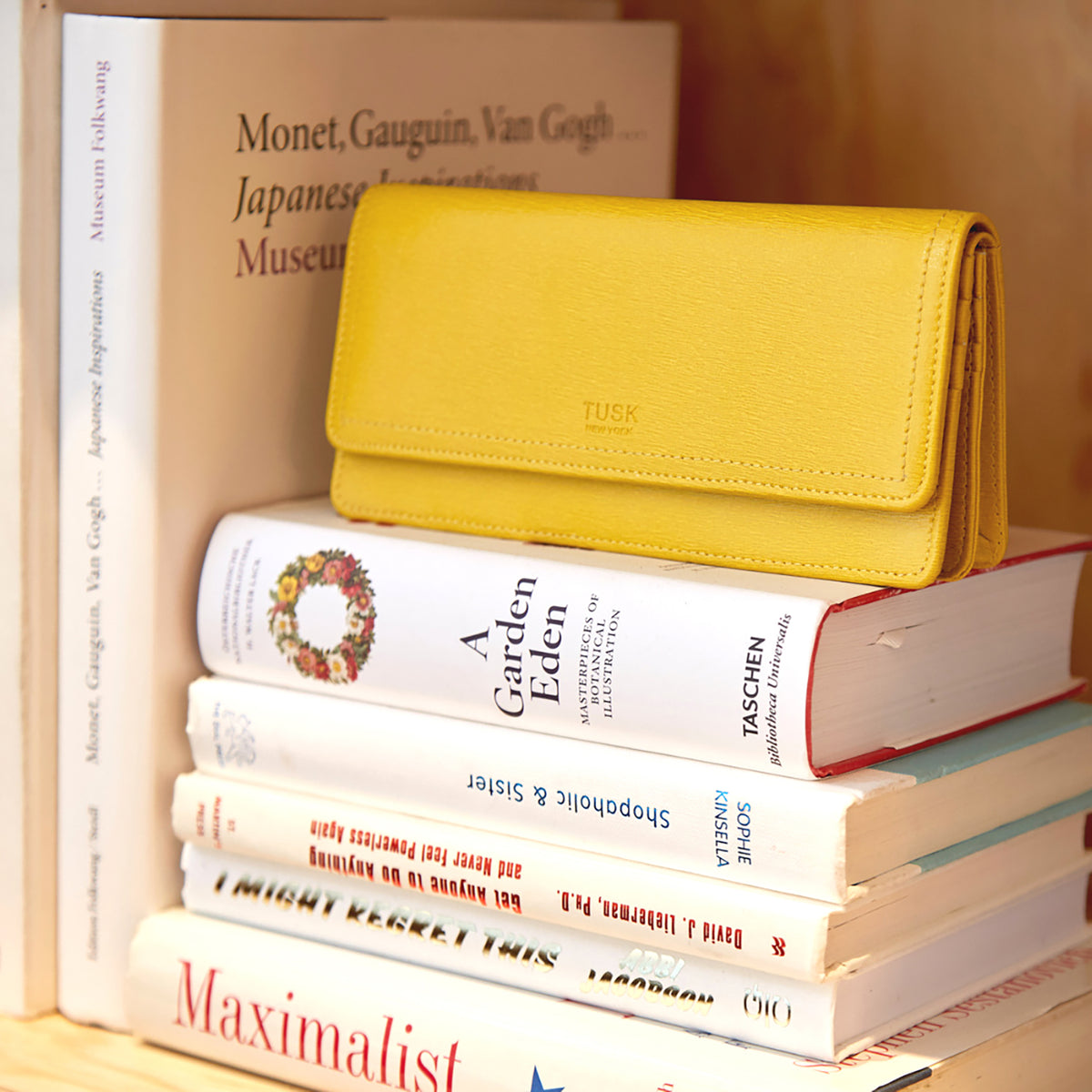  A yellow wallet standing on a stack of books with white covers - SUN